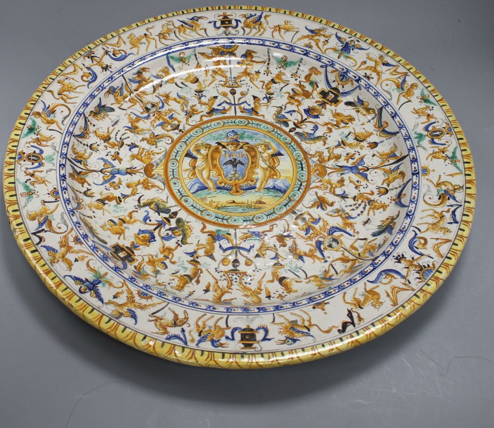 A 19th century Italian 17th century style maiolica charger, decorated with cherubs flanking a cartouche within bands of stylised beasts